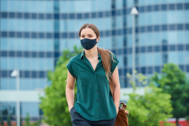 Junge Frau mit einer schwarzen Gesichtsmaske in der Stadt