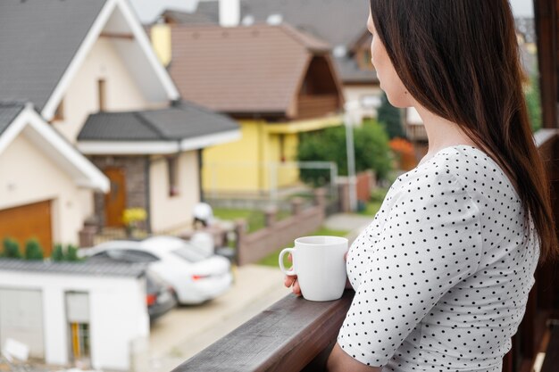 Junge Frau mit einer weißen Tasse in der Hand