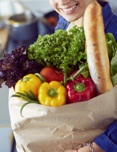 Junge Frau mit Einkaufstüte mit Gemüse in der Küche
