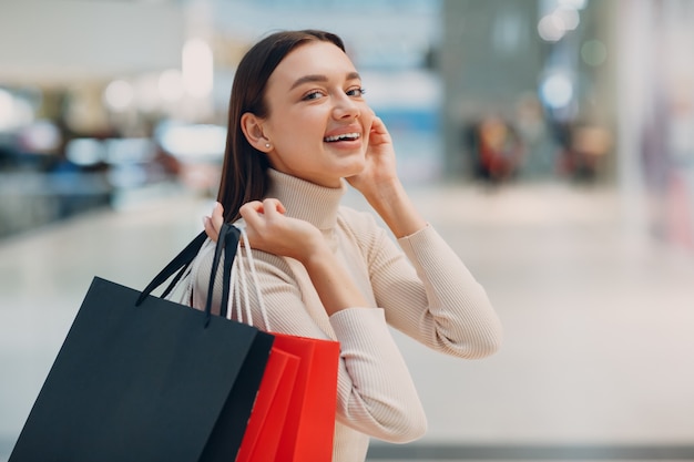 Junge Frau mit Einkaufstüten auf Einzelhandelsgeschäften im Sommerstil, die Mode-Lifestyle-Konzept einkaufen