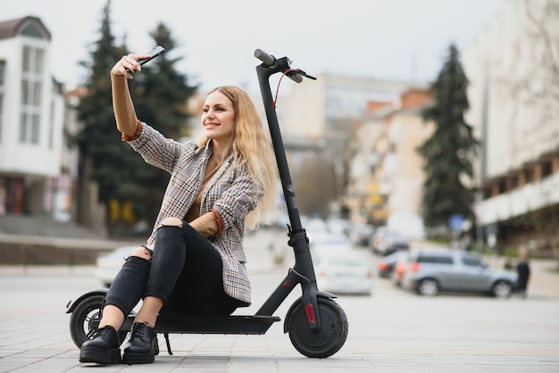 Junge Frau mit Elektroroller in der Stadt