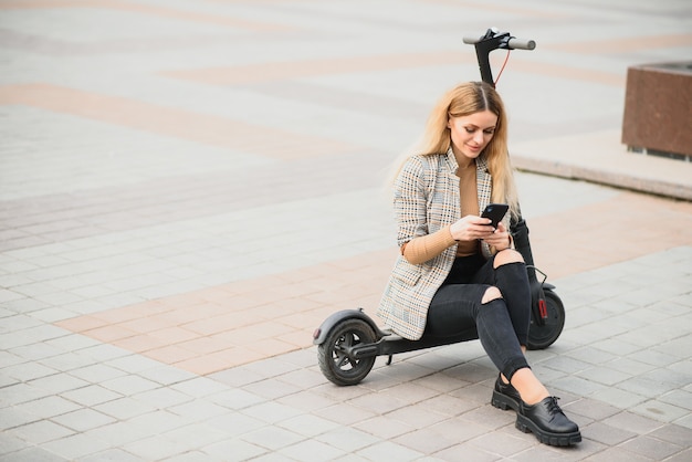 Foto junge frau mit elektroroller in der stadt