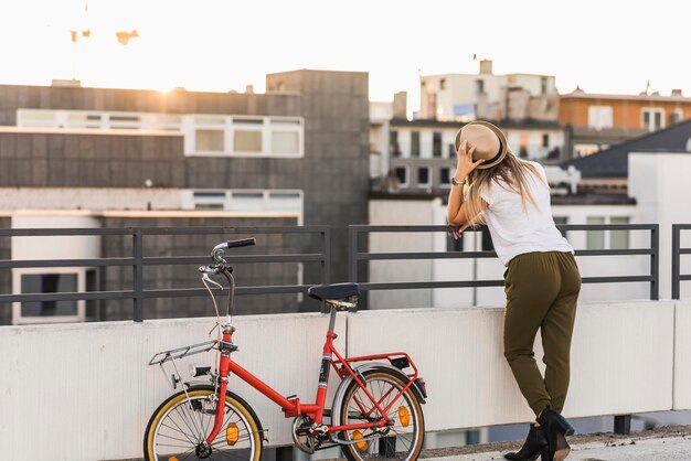 Foto junge frau mit fahrrad lehnt am geländer