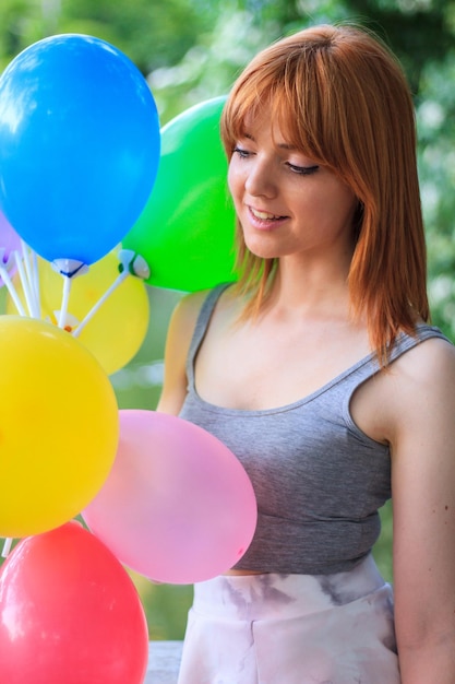 Junge Frau mit farbigen Luftballons im Park