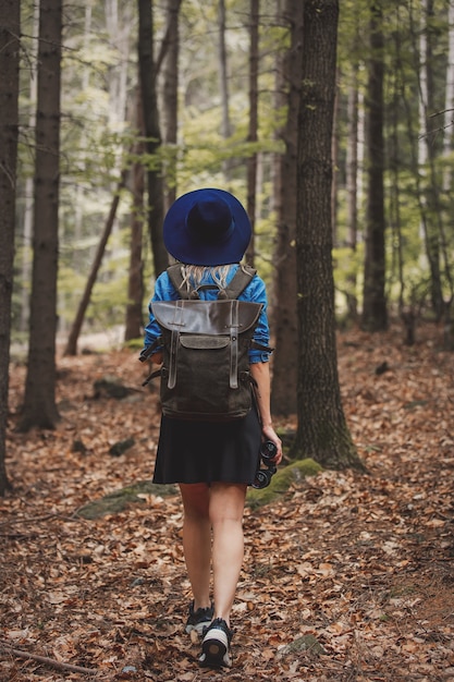 Junge Frau mit Fernglas und Rucksack in einem Wald