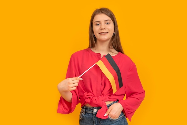 Junge Frau mit Flagge von Deutschland Deutsch lernen Schulmädchen von Deutschland Studentenaustauschprogramm Gelber Hintergrund