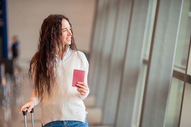 Junge Frau mit Gepäck im internationalen Flughafen. Fluggast in einer Flughafenlounge, die auf Flugflugzeuge wartet