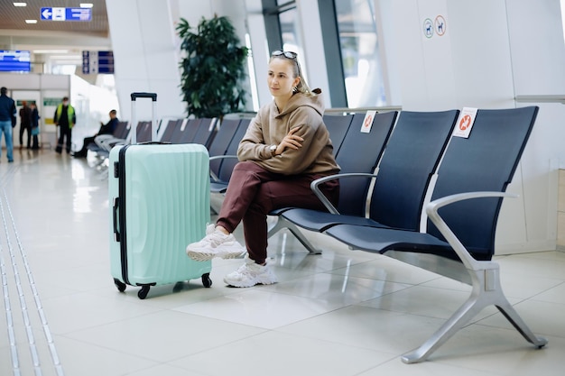 Junge Frau mit Gepäck sitzt im Wartezimmer des Flughafens