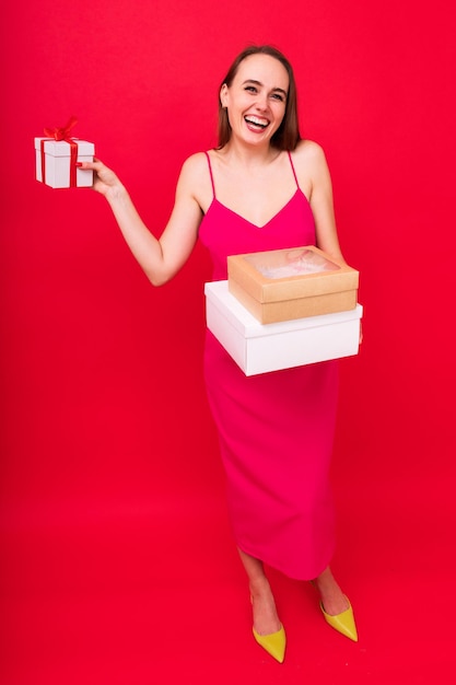 Junge Frau mit Geschenken in ihren Händen auf rotem Hintergrund Weihnachtstradition Geschenke zu geben