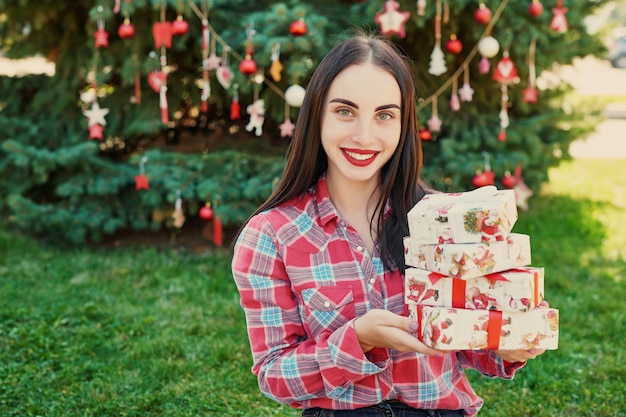 junge Frau mit Geschenken nahe einem Weihnachtsbaum, Weihnachten im Juli auf Natur