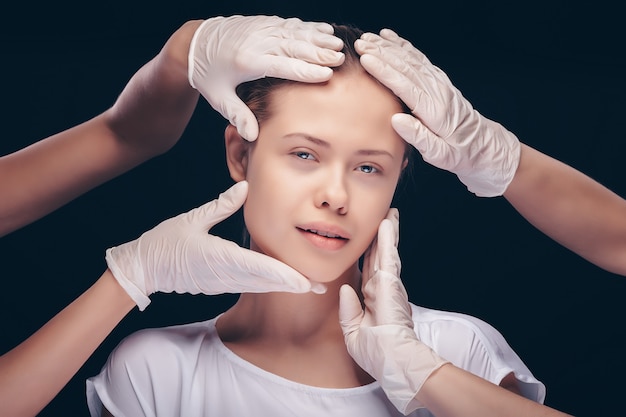 Junge Frau mit geschlossenen Augen, die eine ärztliche Untersuchung ihrer Gesichtshaut durch plastische Ärzte haben