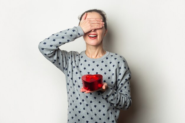 Junge Frau mit geschlossenen Augen freut sich über das Geschenk auf hellem Hintergrund. Valentinstag, Geburtstag. Banner.