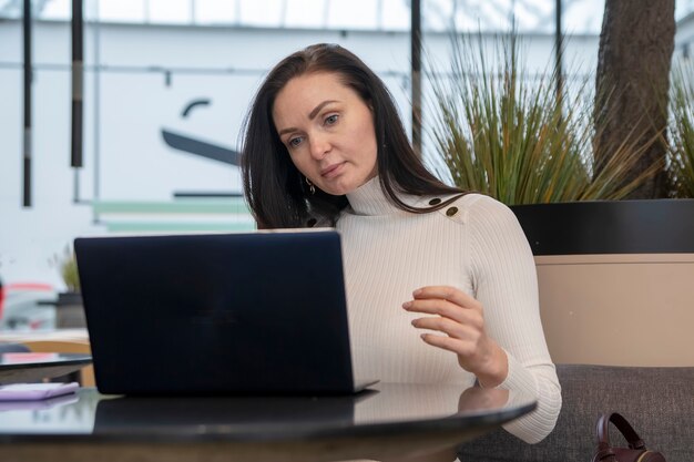 Junge Frau mit Gesichtsschutzmaske arbeitet am Laptop im Café