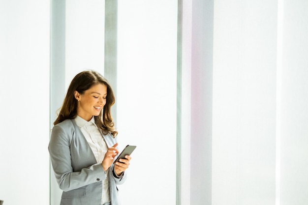 Junge Frau mit Handy am Fenster