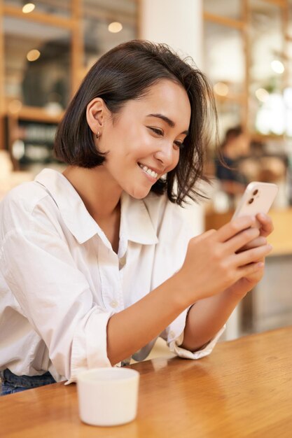 Junge Frau mit Handy am Tisch