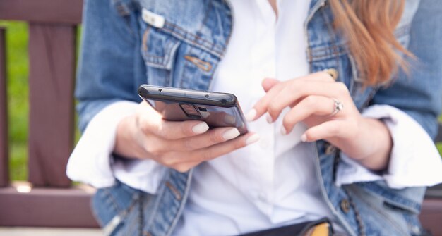 Junge Frau mit Handy im Freien.