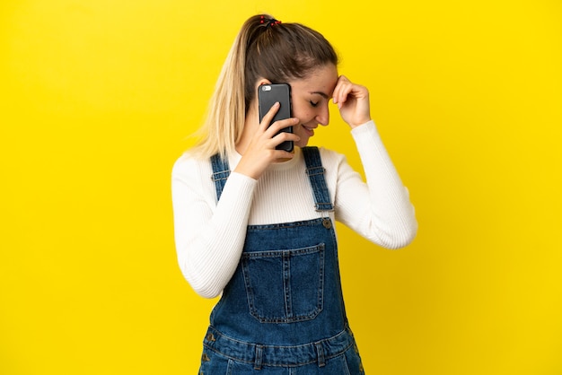 Junge Frau mit Handy über isolierten gelben Hintergrund lachen laugh