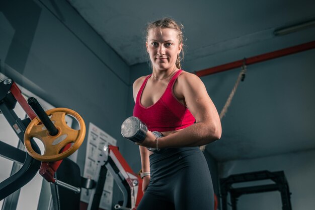 Foto junge frau mit hanteln im fitnessstudio porträt einer jungen attraktiven frau, die fitnesstraining macht