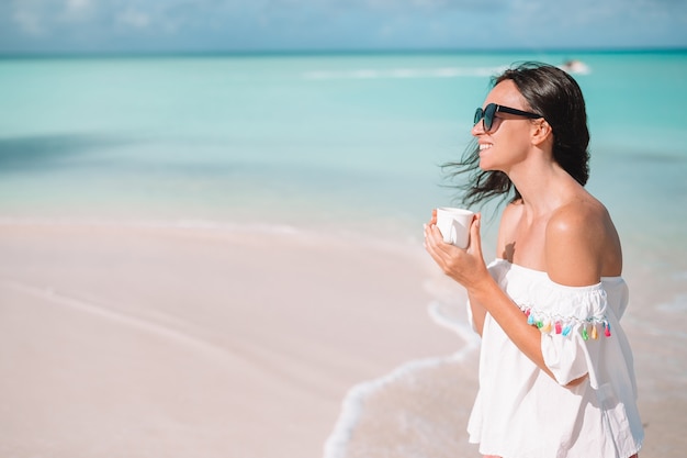 Junge Frau mit heißem Kaffee Strandansicht genießend