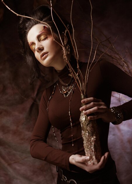 Junge Frau mit hellem Make-up mit trockenen Zweigen