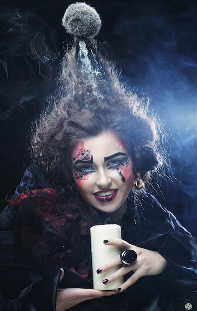 Junge Frau mit hellem Make-up trägt Karnevalskostüm mit einer Kerze Halloween-Bild