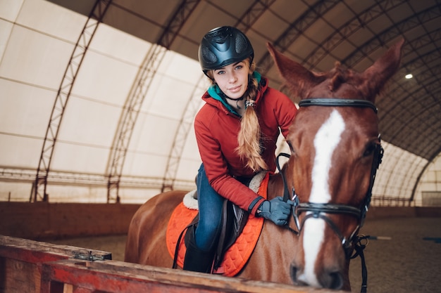 Junge Frau mit Helm, der das Pferd reitet