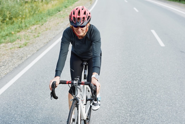 Junge Frau mit Helm, die draußen auf einem Rennrad fährt