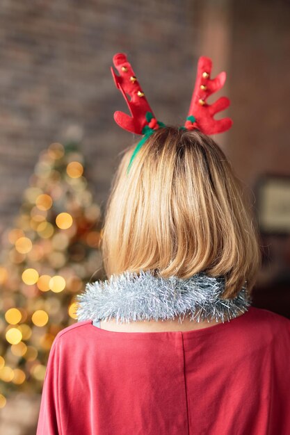 Junge Frau mit Hirschgeweih Stirnband mit Blick auf geschmückten Weihnachtsbaum