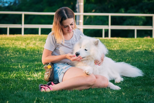 Junge Frau mit Hund sitzt auf dem Gras