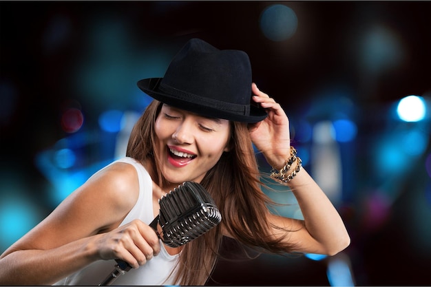Junge Frau mit Hut singt ins Mikrofon