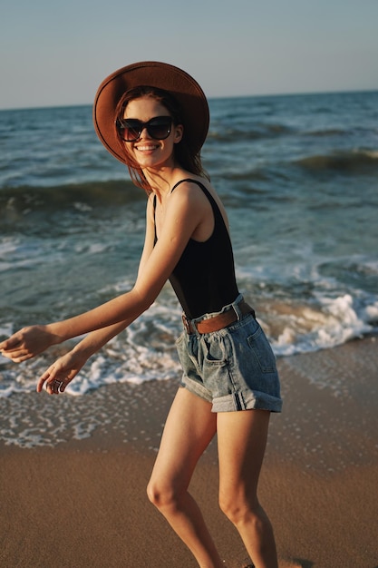 Junge Frau mit Hut steht am Strand