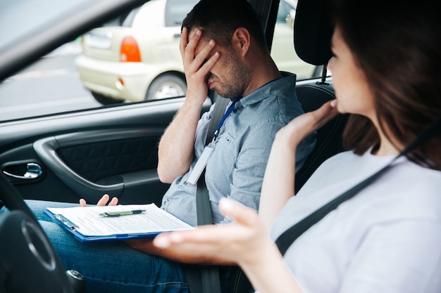 Junge Frau mit ihrem Autolehrer in einem Auto