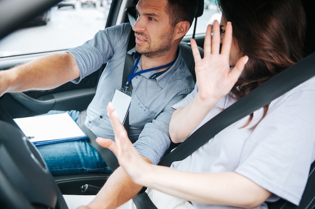 Junge Frau mit ihrem Autolehrer in einem Auto