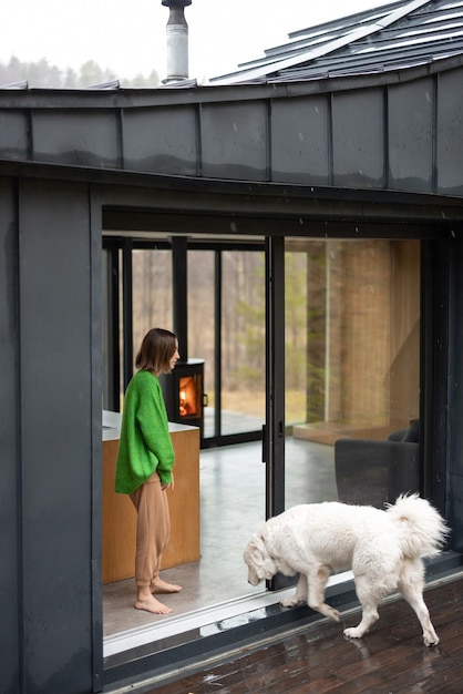 Junge Frau mit ihrem Hund im modernen Haus auf Natur