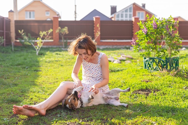 Junge Frau mit ihrem Jack Russell Terrier Hund, der draußen auf dem Gras spielt