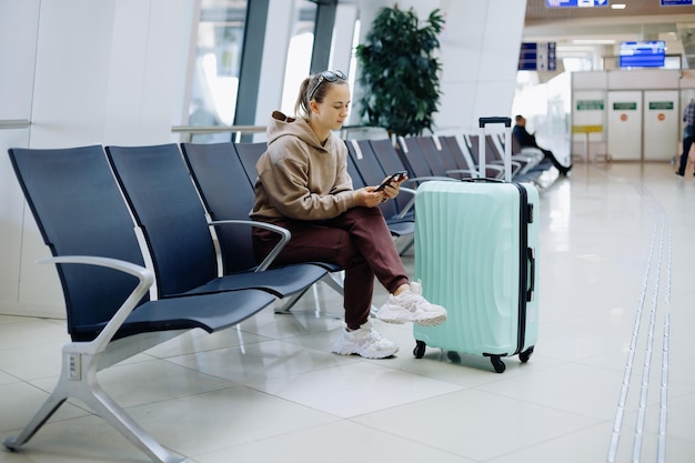 Junge Frau mit ihrem Smartphone am Flughafen