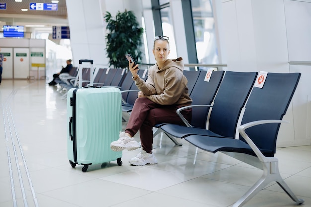 Junge Frau mit ihrem Smartphone am Flughafen