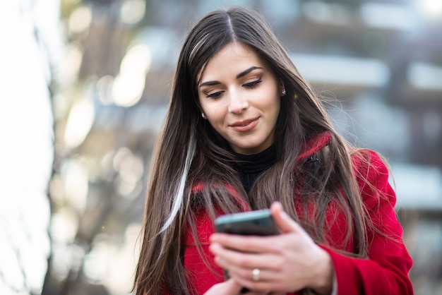 Junge Frau mit ihrem Smartphone beim Spaziergang in einer Stadt