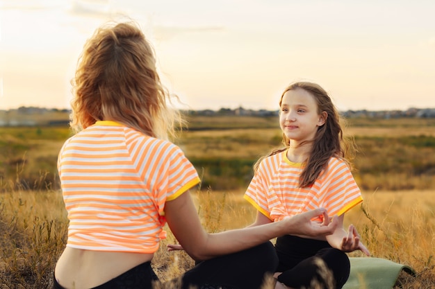 Junge Frau mit ihrer Tochter, die Yoga im Freien macht