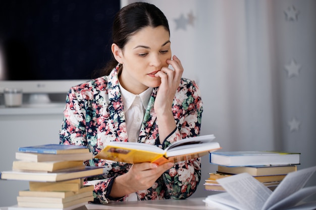 Junge Frau mit Interesse, die ein Buch in der Bibliothek liest