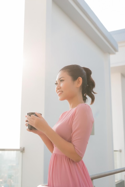 Junge Frau mit Kaffeetasse lächelnd in die Kamera schaut