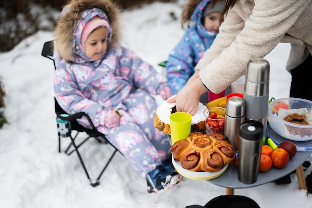 Junge Frau mit Kindern im Winterwald bei einem Picknick