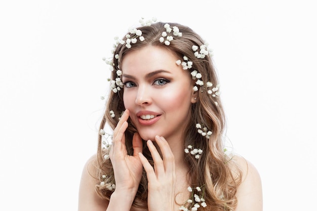 Junge Frau mit kleinen weißen Blumen im Haar. Schöne sanfte lächelnde Blondine. Zärtlichkeit und Romantik. Weißer Hintergrund.