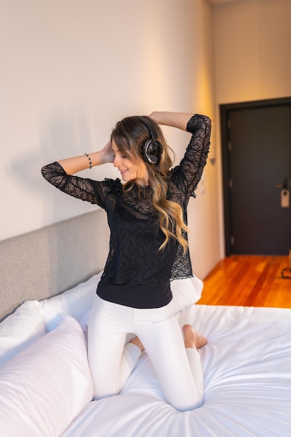 Junge Frau mit Kopfhörern genießt Musik auf dem Bett