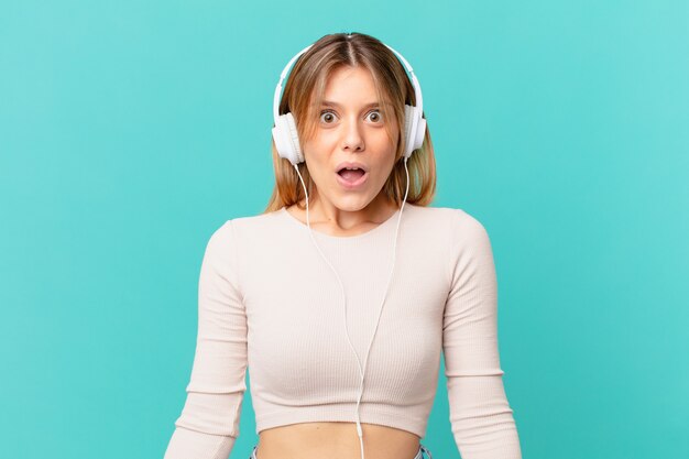 Junge Frau mit Kopfhörern sieht sehr schockiert oder überrascht aus