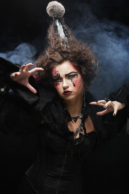 Junge Frau mit kreativem Make-up und Frisur posiert auf dunklem Hintergrund Partyzeit und Halloween