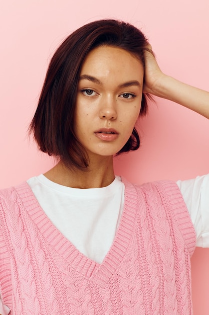 Junge Frau mit kurzen Haaren und einem rosa Pullover rosa Hintergrund