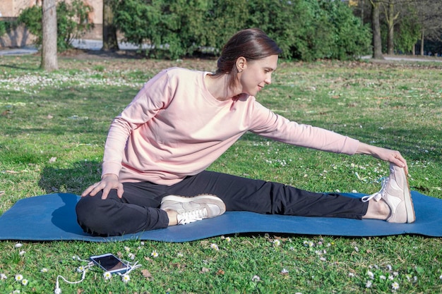 Junge Frau mit langen Haaren beim Yoga auf der Matte im Stadtpark. Atemübungen und psychische Gesundheit