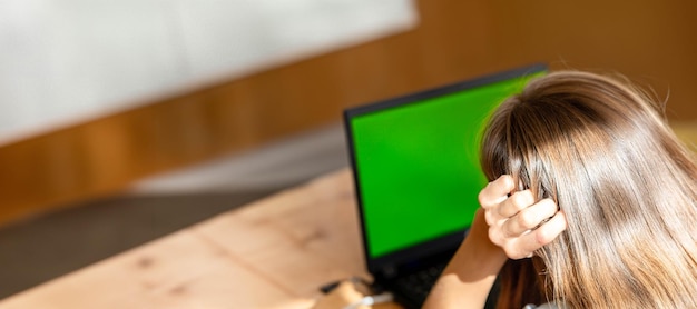 Foto junge frau mit langen haaren benutzt ihren laptop mit grünem bildschirm rückwand banner kopierraum