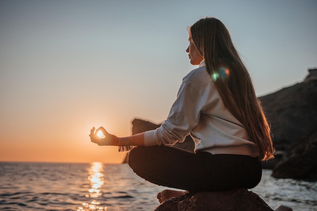 Junge Frau mit langen Haaren in Sportbekleidung und Armbändern im Boho-Stil, die im Freien auf einer Yogamatte üben